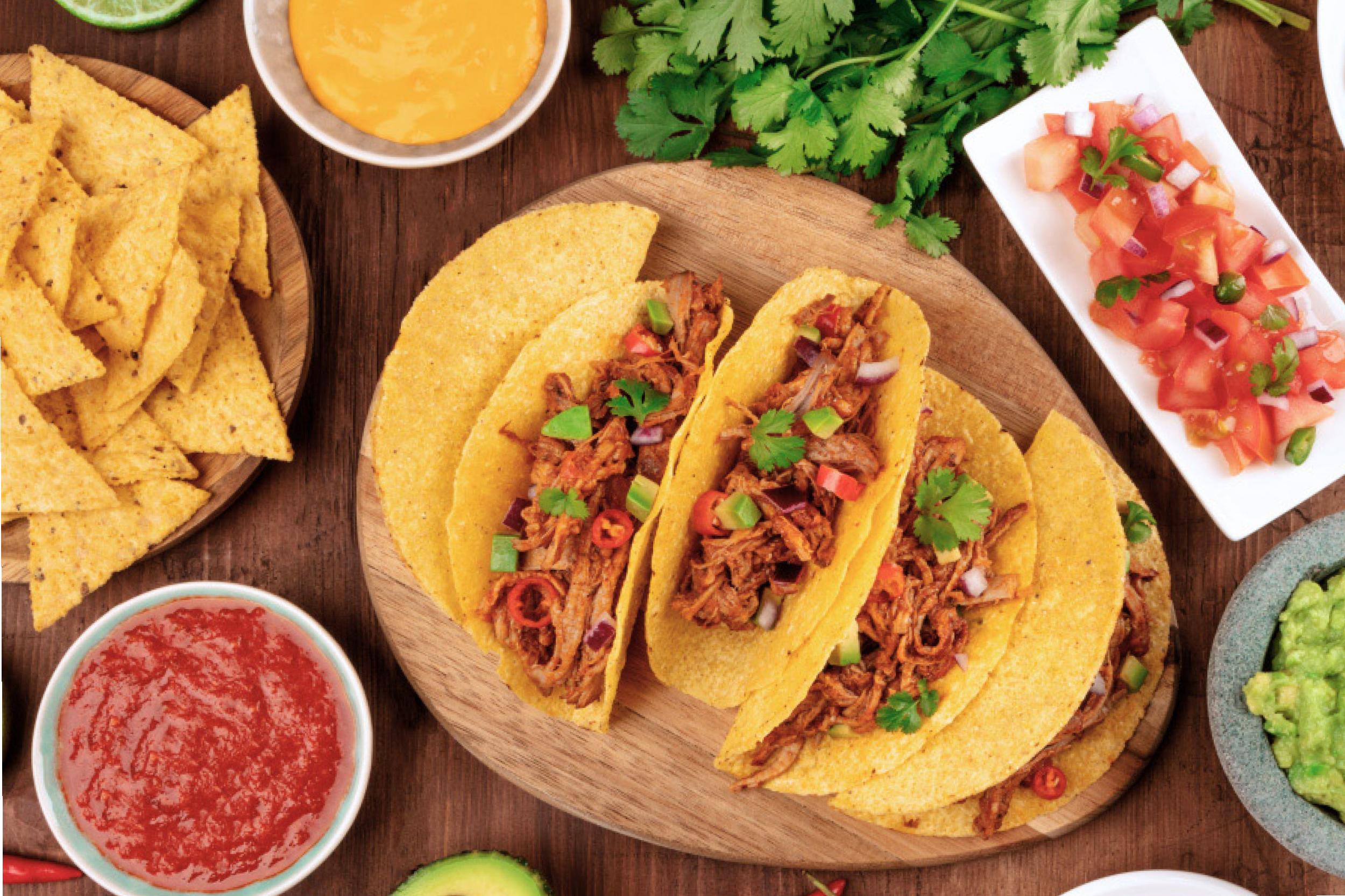 Three tacos, chopped tomatoes, salsa and cilantro